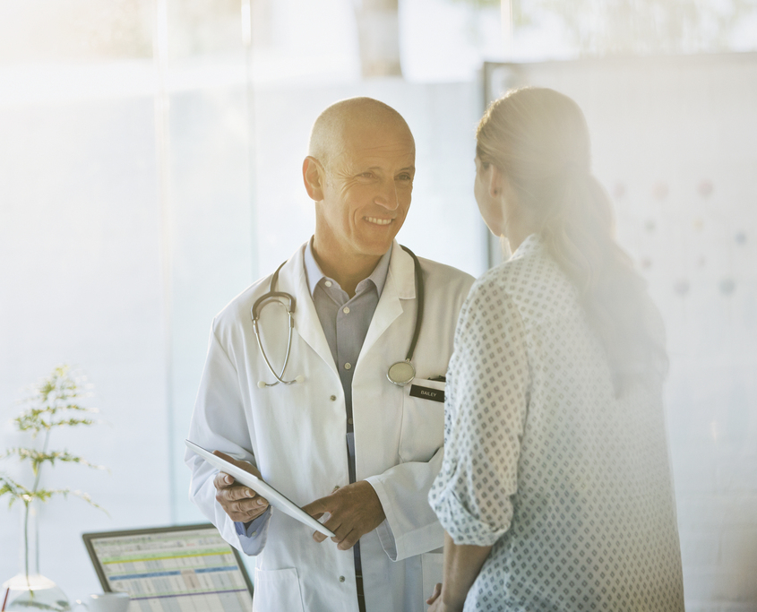 Smiling doctor showing digital tablet to patient in doctors office