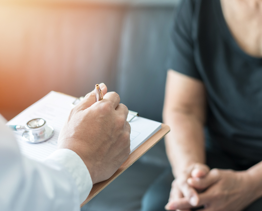 Doctor taking notes while speaking with patient